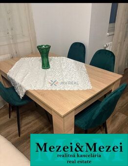 Esstisch mit einer Vase und grünen Stühlen, Holzboden in einer 2-Zimmer-Wohnung.