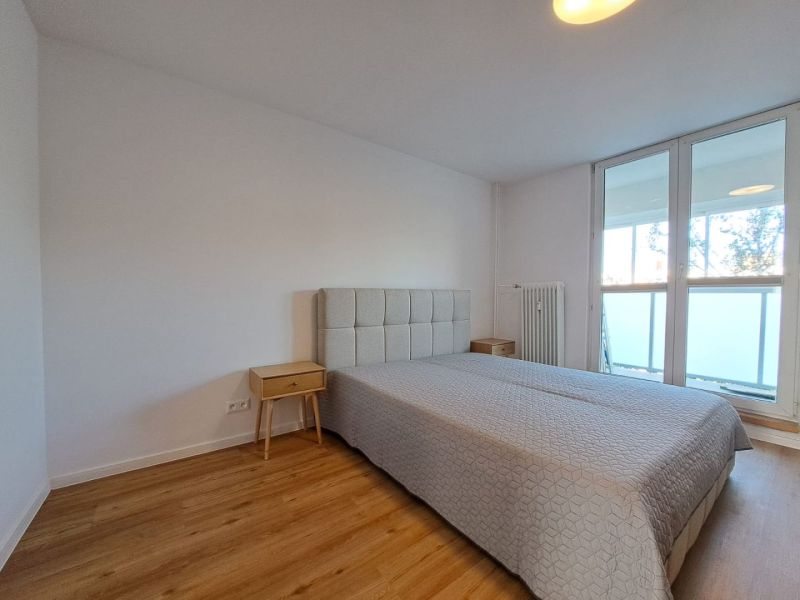 Schlafzimmer in einer 2-Zimmer-Wohnung mit einem Bett und einem Boden in Holzoptik.