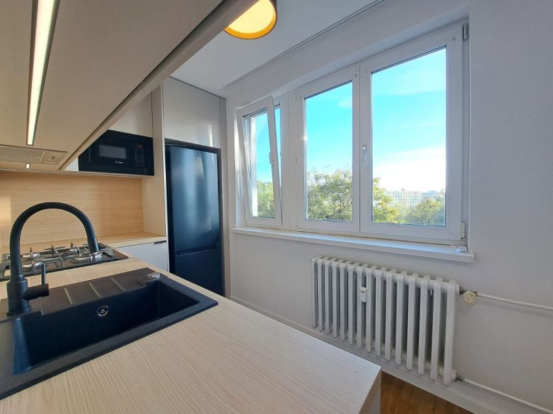 Küche in einer 2-Zimmer-Wohnung mit Holzboden und großen Fenstern.