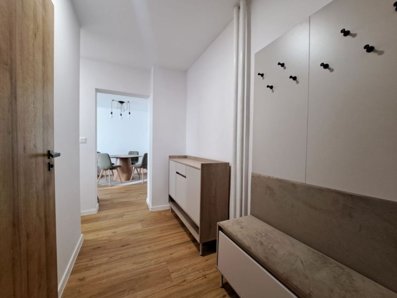 Der Flur in einer 2-Zimmer-Wohnung mit einem Boden in Holzoptik, einem Flurmöbel und einem Essbereich.