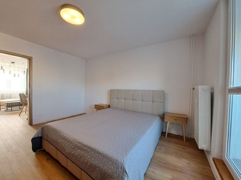 Schlafzimmer mit Bett und Nachttischen, Boden mit Holzdekor in einer 2-Zimmer-Wohnung.