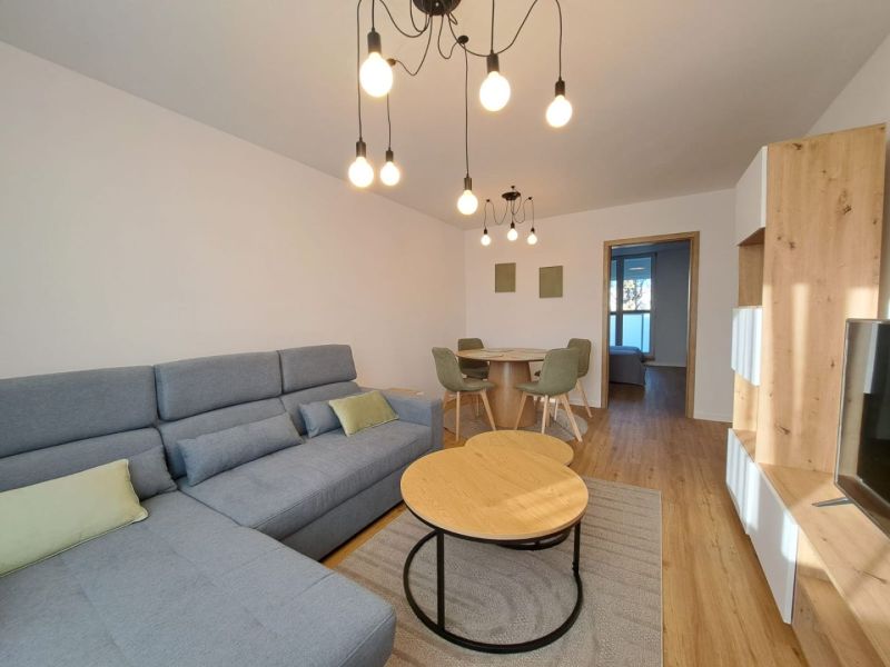 Wohnzimmer mit Sofa, Holzboden und Esstisch in einer Zweizimmerwohnung.