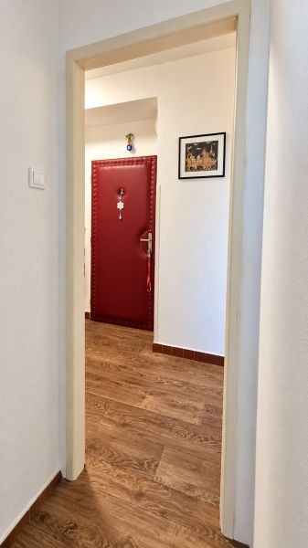 Ein Flur mit roten Türen und einem Boden in Holzoptik in einer 3-Zimmer-Wohnung.