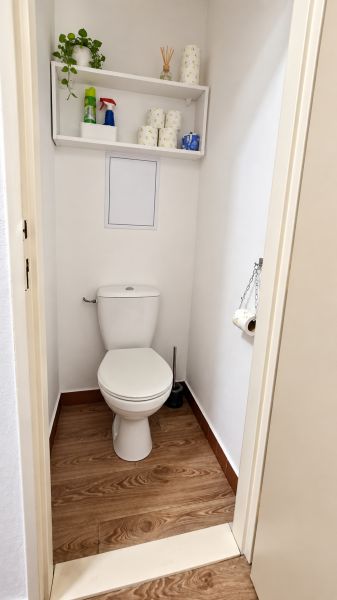 Toilette mit Regal und Boden in Holzoptik in einer 3-Zimmer-Wohnung.