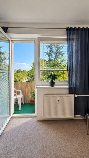 Wohnzimmer in einer 3-Zimmer-Wohnung mit Blick auf den Balkon und Grünflächen.