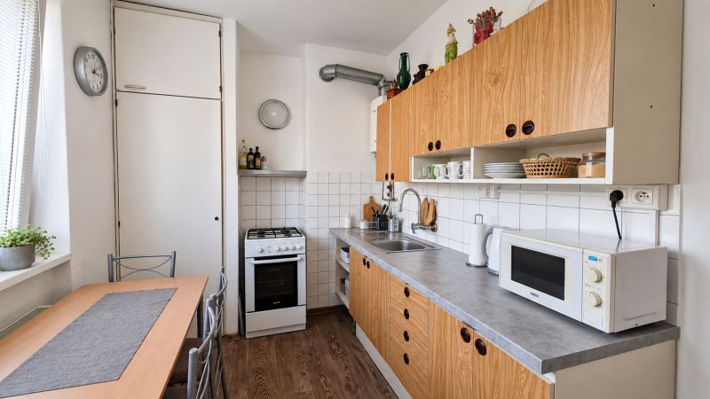 Küche in einer 3-Zimmer-Wohnung mit Küchenzeile, Geräten und Bodenbelag in Holzoptik.