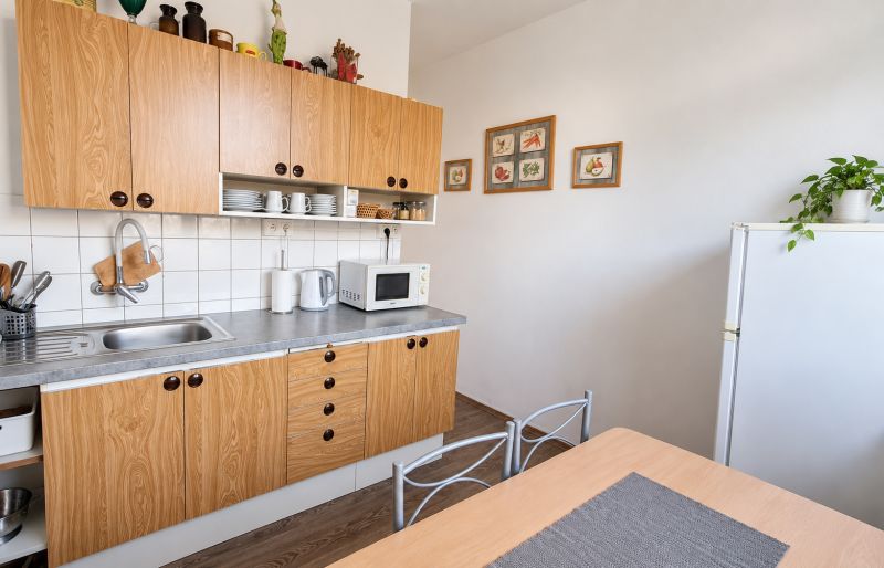 Küche in einer 3-Zimmer-Wohnung mit Holzboden, weißen Wänden und Holzschränken.