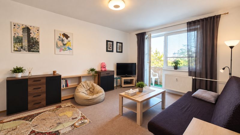 Wohnzimmer in einer 3-Zimmer-Wohnung mit bequemen Sitzgelegenheiten und Zugang zum Balkon.