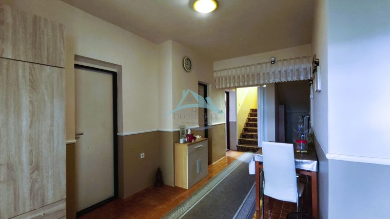 Flur in einem Einfamilienhaus mit Teppichtreppe, Tisch und Boden mit Holzdekor.