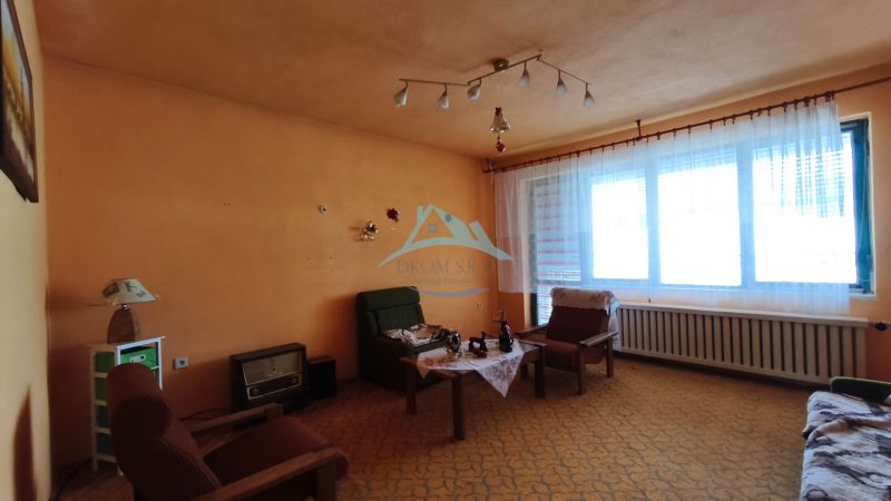 Wohnzimmer in einem Einfamilienhaus mit orangefarbenen Wänden und Vintage-Möbeln.