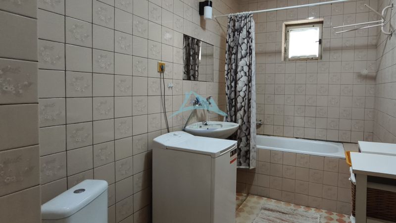 Badezimmer mit Badewanne, Waschbecken und Waschmaschine in einem Einfamilienhaus.