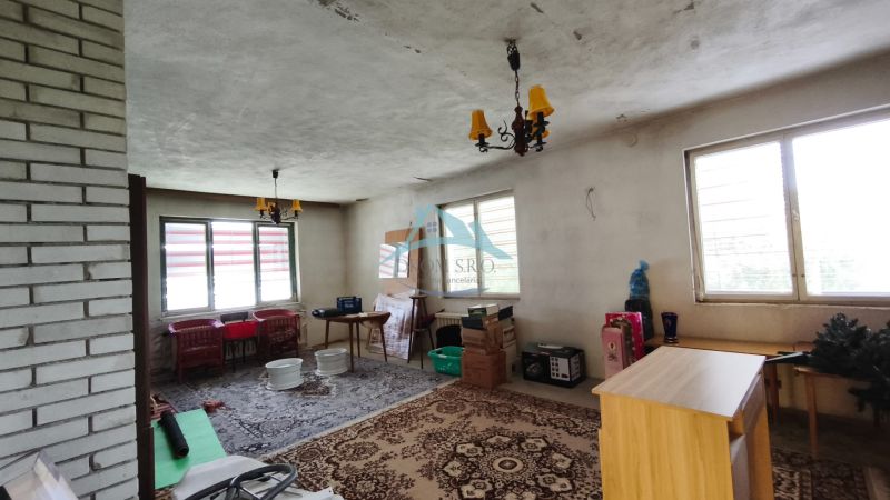 Innenraum eines Einfamilienhauses mit Kunststofffenstern, Ziegelwand und dekorativem Teppich.