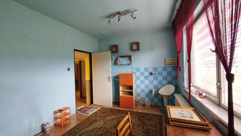 Ein Zimmer in einem Einfamilienhaus mit Fliesen, einem Holzboden und einem großen Fenster.