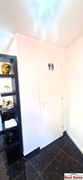 Innenraum von Geschäftsräumen mit einer Tür zur Toilette und einem dekorativen Regal.