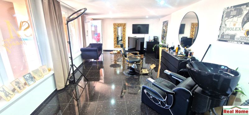 Friseursalon mit schwarzem Granitboden, großen Spiegeln und bequemen Stühlen.