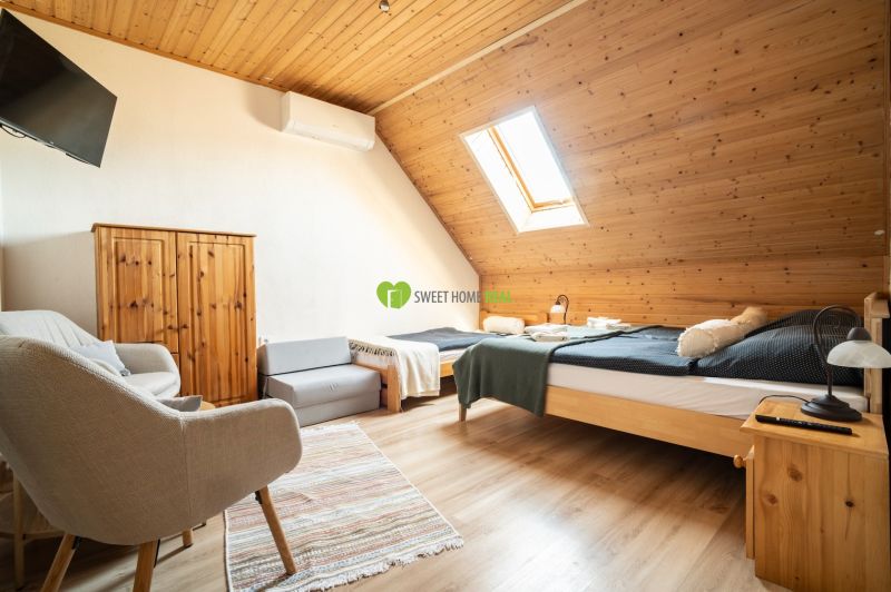 Dachzimmer mit Bett, Sessel, Dachfenster und Holzboden.