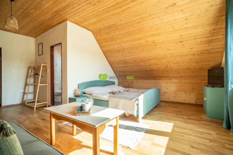 Dachzimmer mit Bett, Tisch und Boden mit Holzdekor im Hotel.