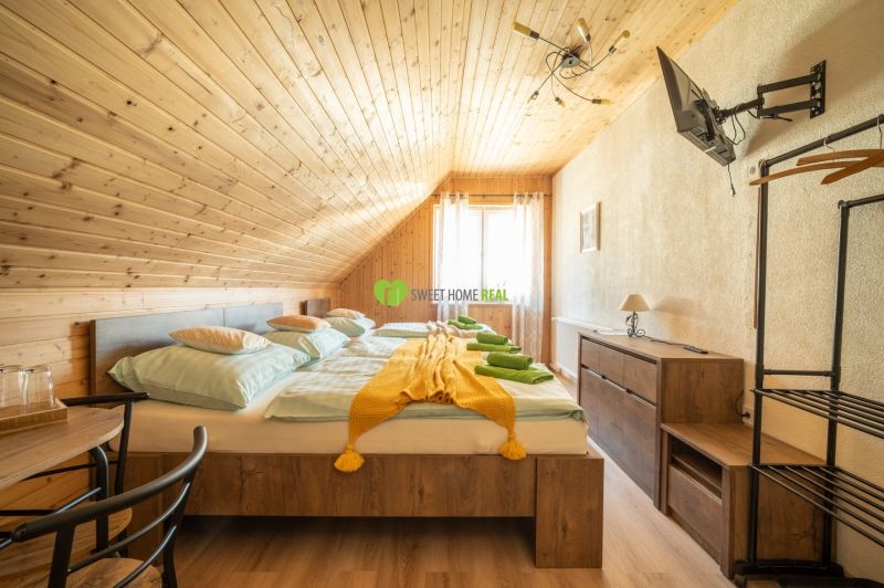 Ein Zimmer mit Holzverkleidung, einem Doppelbett, einem Fernseher und einem Boden mit Holzdekor. Hotels und Pensionen.