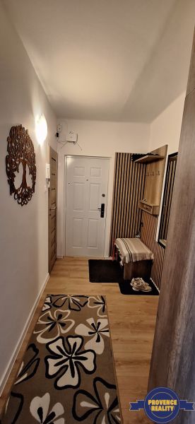 Flur in einer 3-Zimmer-Wohnung mit Holzboden und einem Teppich mit Blumenmuster.