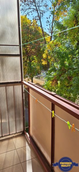 Balkon einer 3-Zimmer-Wohnung in Komárno mit Blick auf grüne Bäume.