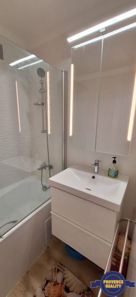 Badezimmer in einer 3-Zimmer-Wohnung mit Badewanne, Spiegelschrank und Boden mit Holzdekor.