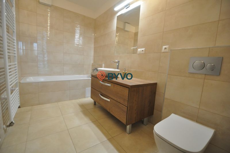 Badezimmer in einer 3-Zimmer-Wohnung mit Badewanne, Waschbecken und Schrank mit Holzdekor.