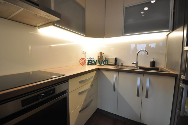Küche in einer 3-Zimmer-Wohnung mit einer linearen Küchenzeile und einem Boden in Holzoptik.