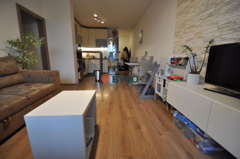 Wohnzimmer in einer 3-Zimmer-Wohnung mit Holzboden, Sitzgarnitur und Küche.