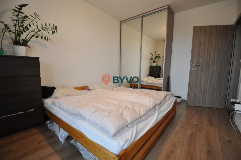 Schlafzimmer mit Bett, Schrank mit Spiegel und Boden mit Holzdekor in einer 3-Zimmer-Wohnung.