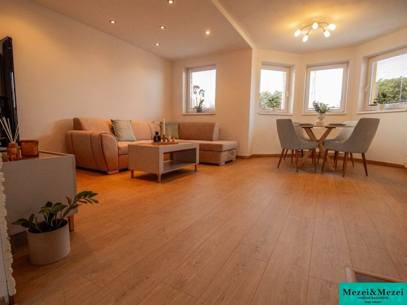 Wohnzimmer in einem Einfamilienhaus mit Holzboden und bequemen Sitzgelegenheiten.