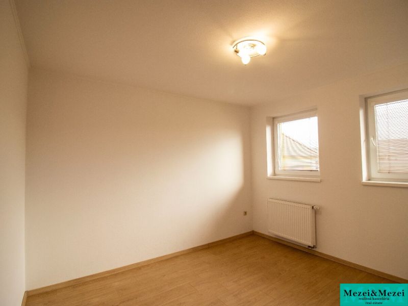 Ein Zimmer in einem Einfamilienhaus mit einem Holzboden und zwei Fenstern.