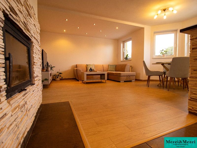 Wohnzimmer in einem Einfamilienhaus mit Kamin und Boden in Holzoptik.