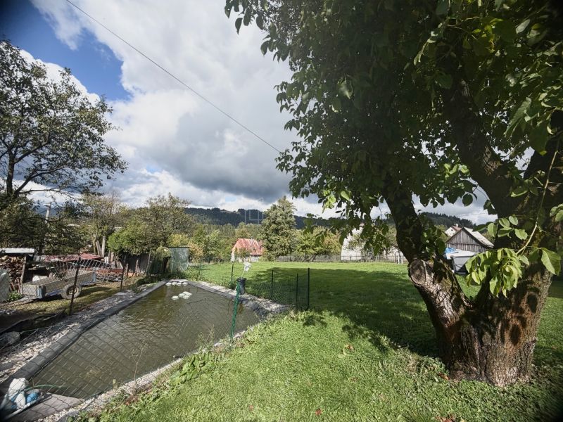 Ein Garten mit einem Teich und Bäumen auf einem Grundstück in Oščadnica in der Straße Košariská.