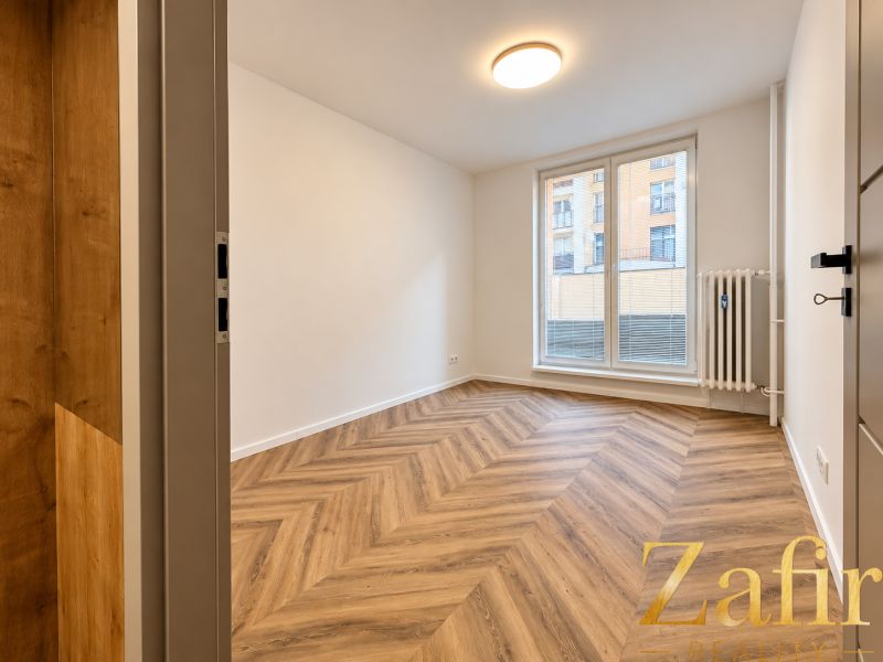 Innenraum einer 3-Zimmer-Wohnung mit Holzboden, weißen Wänden, großem Fenster.