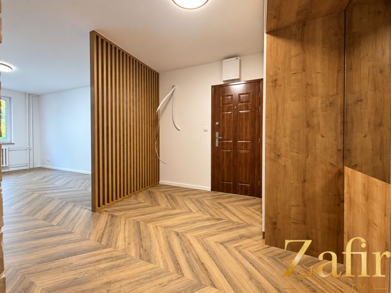 Innenraum einer 3-Zimmer-Wohnung mit Holzboden und Holzwand.