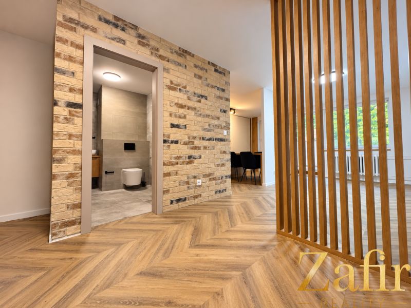 Innenraum einer 3-Zimmer-Wohnung mit Holzboden und Ziegelwand.