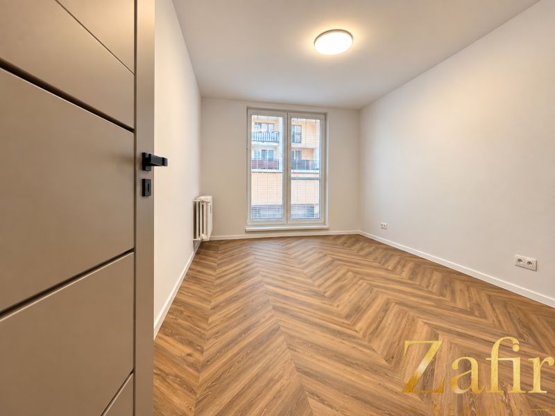 Ein Zimmer in einer 3-Zimmer-Wohnung mit einem Boden in Holzoptik und einem französischen Fenster.