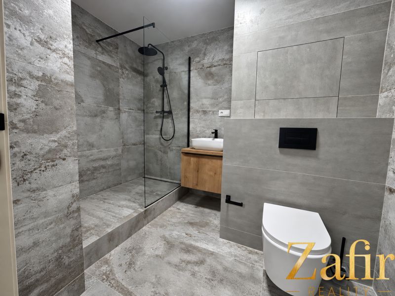 Badezimmer in einer 3-Zimmer-Wohnung mit einer modernen Duschkabine und eleganten Fliesen.