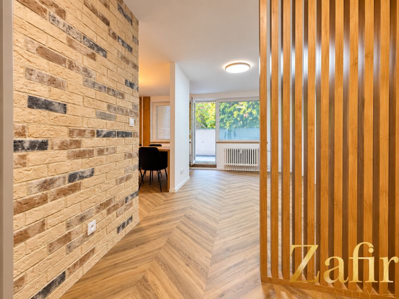 Innenraum einer 3-Zimmer-Wohnung mit Ziegelwand und Boden in Holzoptik.