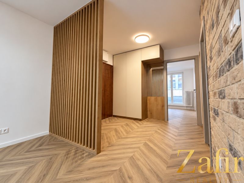 Innenraum einer 3-Zimmer-Wohnung mit gemauerter Wand und Boden in Holzoptik.