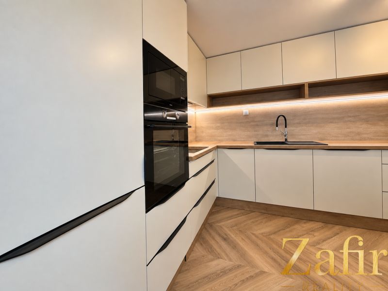Küchenzeile mit weißen Schränken und Holzdekor in einer 3-Zimmer-Wohnung.