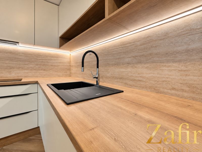 Küche in einer 3-Zimmer-Wohnung mit Holzboden und weißen Schränken.