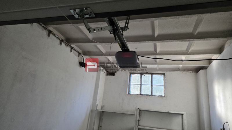 Innenraum einer Garage mit weißen Wänden, einem Fenster und einem Garagentoröffner.