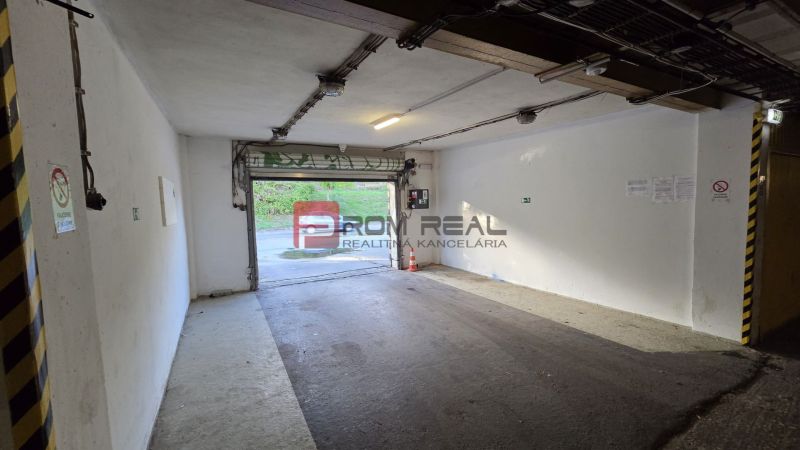 Der Innenraum einer Garage mit offenen Türen, weißen Wänden und einer Ausfahrt nach draußen.