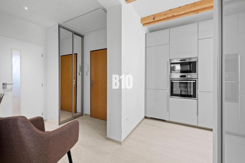 Helle Innenausstattung einer 2-Zimmer-Wohnung mit weißen Wänden, Geräten und Spiegel.