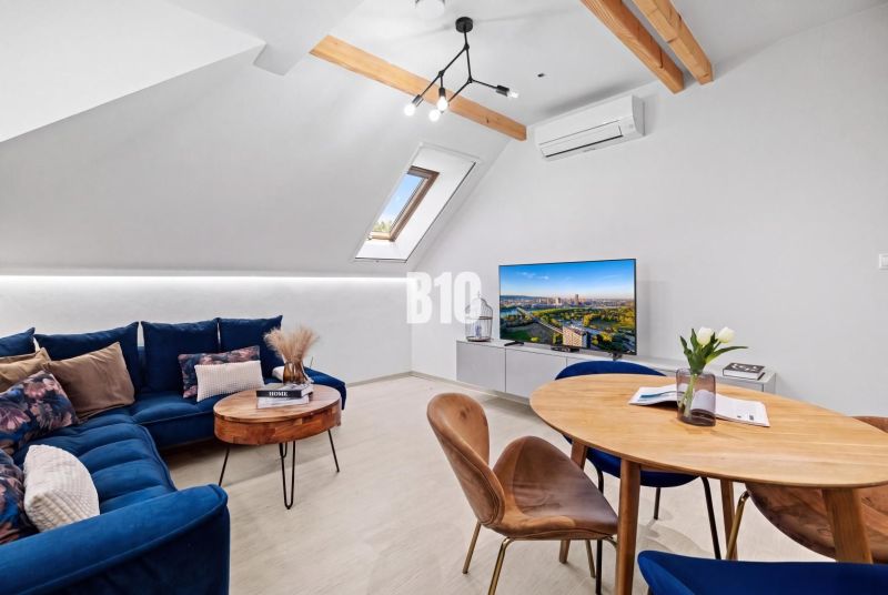 Dachboden-Wohnzimmer mit blauem Sofa, Fernseher und Holzboden, 2-Zimmer-Wohnung.