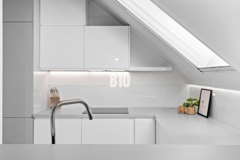 Eine Küche im Dachgeschoss mit Dachfenster und minimalistischem Design in einer 2-Zimmer-Wohnung.