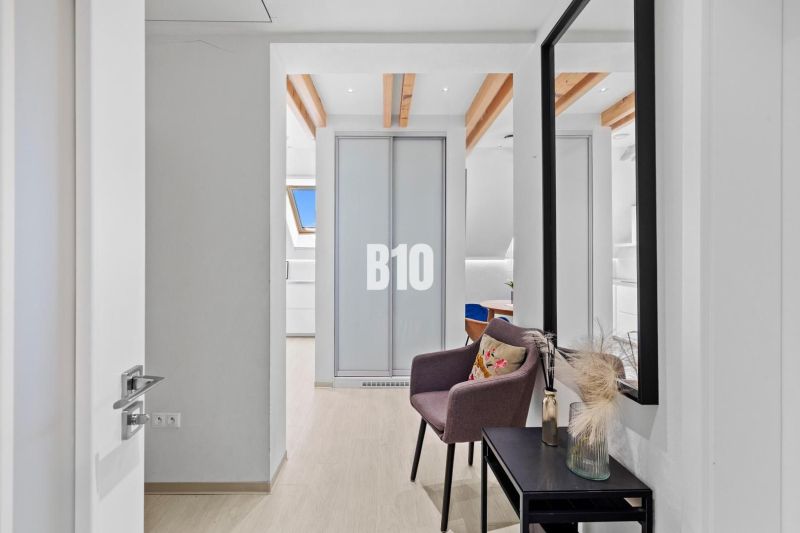 Der Flur in der 2-Zimmer-Wohnung mit einem Boden in Holzoptik und einem Spiegel an der Wand.
