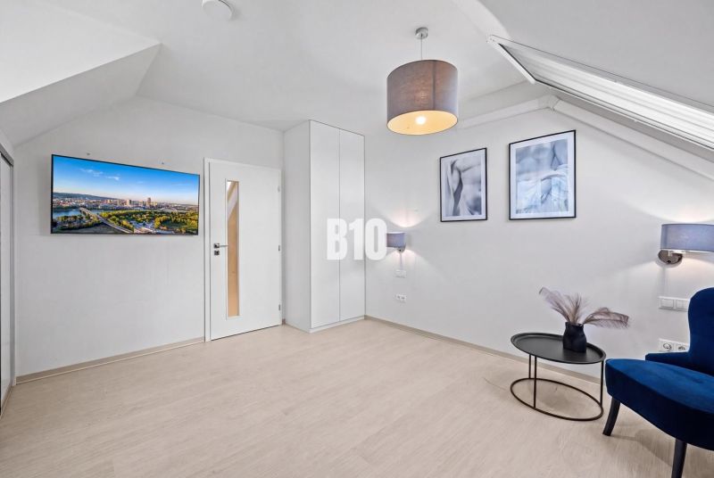 Wohnzimmer mit Holzboden, Fernseher und blauem Stuhl in einer Zweizimmerwohnung.