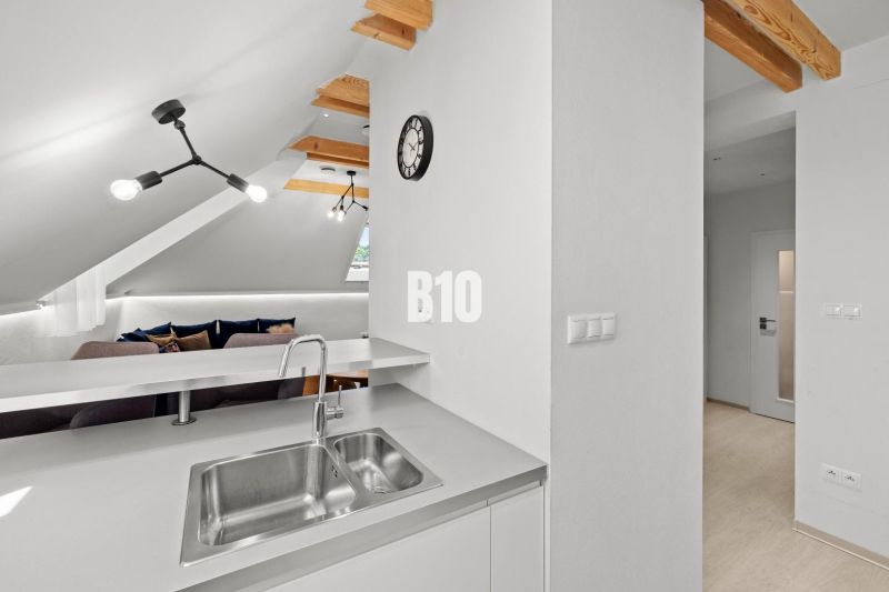 Dachgeschossküche und Wohnzimmer mit Holzelementen in einer Zweizimmerwohnung.